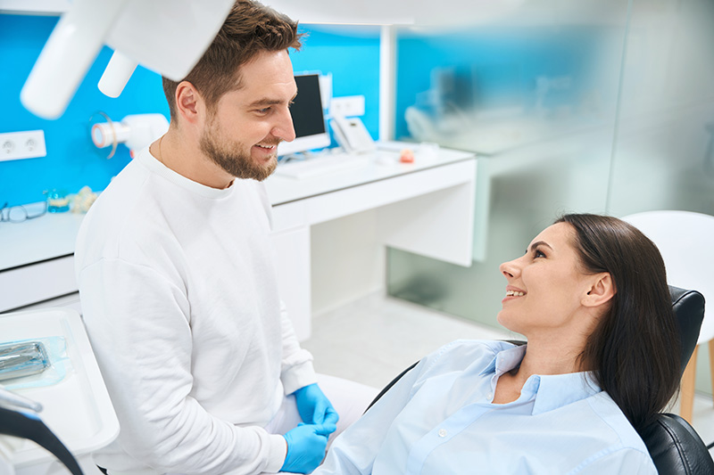 Zahnarzt berät eine Patientin vor der Untersuchung zu ihrer Mund- und Zahngesundheit im Behandlungsstuhl.